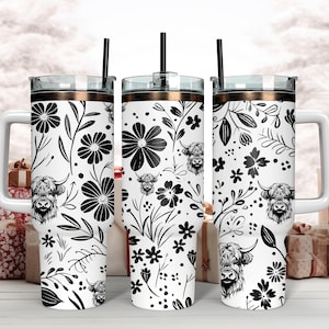 May include: Three stainless steel tumblers with black and white floral and highland cow designs. The tumblers have a gold lid and a straw.