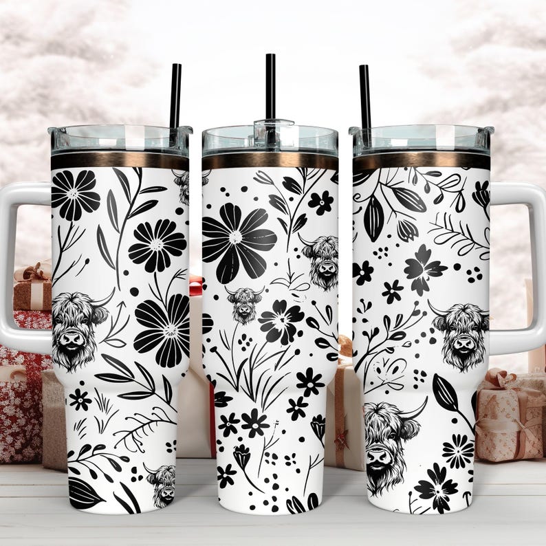 May include: Three stainless steel tumblers with black and white floral and highland cow designs. The tumblers have a gold lid and a straw.