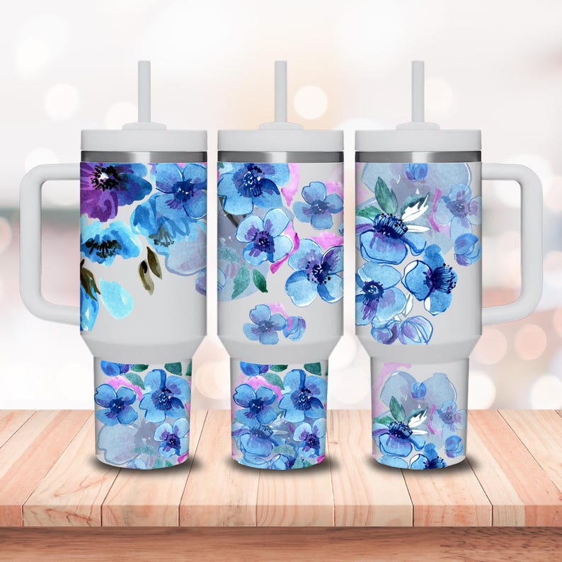 May include: Three white stainless steel tumblers with blue and purple watercolor floral designs. Each tumbler has a lid and a straw.