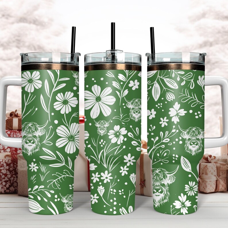 May include: Three green stainless steel tumblers with a white floral and highland cow pattern. The tumblers have lids and straws.