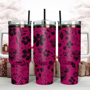 May include: Three stainless steel tumblers with a pink floral and highland cow design. The tumblers have lids and straws.