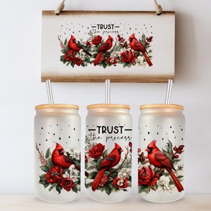 May include: A set of three frosted glass tumblers with wooden lids and metal straws, featuring a red cardinal bird design with red roses and white flowers. The text "TRUST the process" is printed on the tumblers and wooden sign.