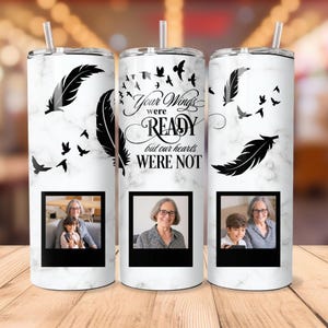 May include: Three white stainless steel tumblers with black marble pattern and black feather designs. The tumblers have a black and white photo of a woman and a child in a black frame. The tumblers have the text "Your Wings Were Ready But Our Hearts Were Not".