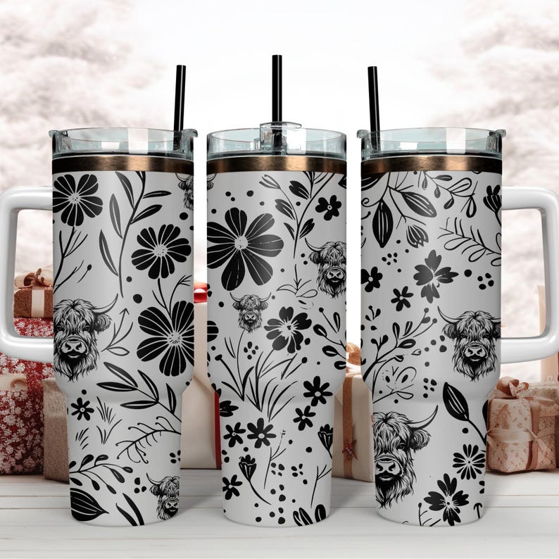 May include: Three stainless steel tumblers with a black and white floral design featuring highland cattle. The tumblers have a gold lid and a straw.