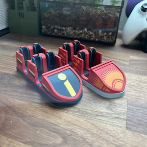 May include: Two red and black roller coaster cars with different designs. One car has a yellow lightning bolt design and the other has a yellow sun design.