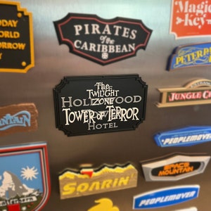 May include: A black and silver metal sign with the text "The Twilight Zone Tower of Terror Hotel" in a stylized font.