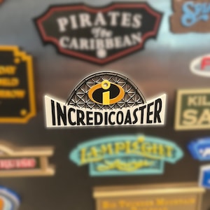 May include: A black and yellow sign with the text "IncrediCoaster" and a stylized image of the Incredibles character,  'Syndrome', in a roller coaster.