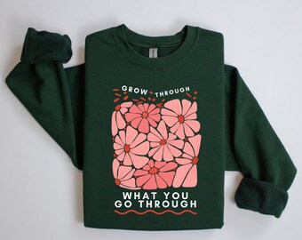 May include: A dark green sweatshirt with a pink floral design and the text "GROW THROUGH WHAT YOU GO THROUGH".