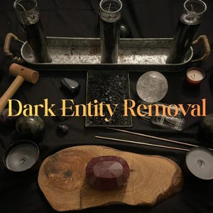 May include: A collection of ritual items including three black pillar candles in a galvanised metal tray, a wooden mallet, a clear crystal sphere, a tray of black stones, two incense sticks, and a dark red faceted stone on a wooden slab with the text Dark Entity Removal.
