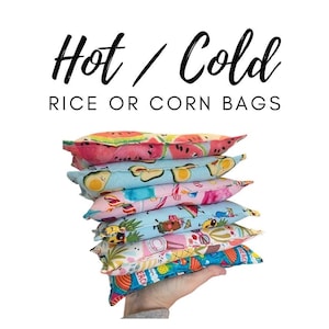 May include: A stack of six colorful hot or cold rice or corn bags. The bags are made of fabric and have different patterns, including watermelon, avocado, and pineapple.