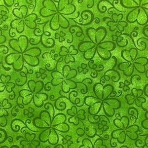 May include: Green fabric with a repeating pattern of shamrocks and swirls.