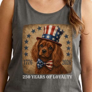 May include: Grey vest top with a patriotic dog illustration. The dog is wearing a red, white, and blue top hat and bow tie. The graphic includes the years 1776 and 2026, and the text "250 YEARS OF LOYALTY".