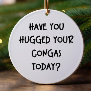 May include: White ceramic bauble with the text "Have you hugged your congas today?" in black lettering.