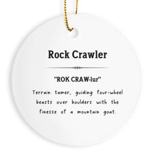 May include: A white ceramic ornament with the text "Rock Crawler" in black. Below, the pronunciation "ROK CRAW-lur" is displayed. The text describes a terrain tamer guiding four-wheel beasts over boulders.