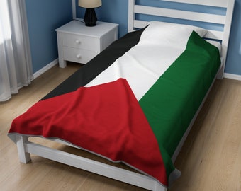 May include: A white twin-sized bed with a black, white, red, and green patterned blanket. The blanket features the colors and design of the Palestinian flag.