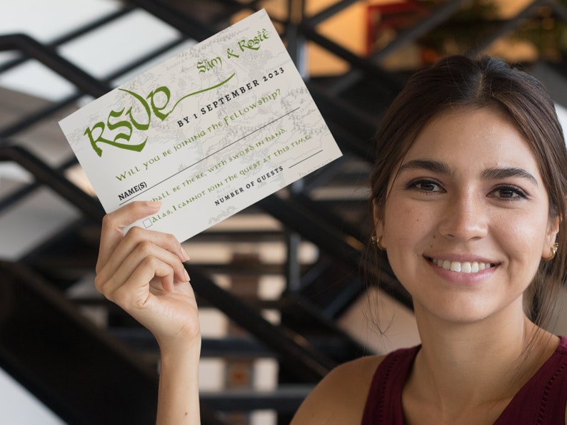 May include: A white RSVP card with green text and a map-like background. The text reads "Sam & Reste BY: SEPTEMBER 2023 WILL you BE JOINING THE Fellowship? NAME(S) hall be there, with sword in hand ALAS, I CANNOT join the quest at this time NUMBER OF GUESTS"