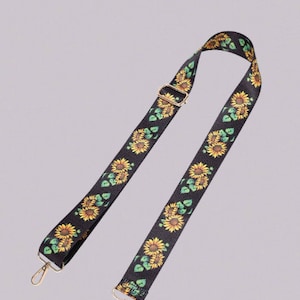May include: Black adjustable strap with a sunflower print. The strap has gold metal hardware and two clasps.