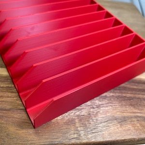 May include: A red plastic organizer with multiple compartments. The organizer is designed to hold small items, such as tools or craft supplies.