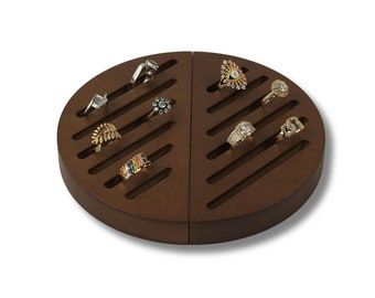 May include: A brown, semi-circular ring display with multiple slots, showcasing various rings. The rings feature diverse designs, including a leaf, a floral pattern, and gemstone arrangements. The display is made of wood and is designed to hold rings.
