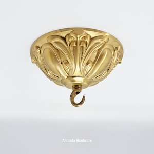 May include: Gold ceiling canopy with a decorative floral design and a hook for hanging a chandelier.