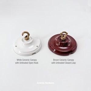 May include: Two ceramic ceiling canopies. One is white with an untreated open hook, and the other is brown with an untreated closed loop. The text on the image reads "Amanda Hardware."