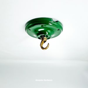 May include: A green ceiling hook with a brass hook. The hook is attached to a circular, green metal plate. The plate has a glossy finish and is mounted on a white surface. The text "Amanda Hardware" is at the bottom.