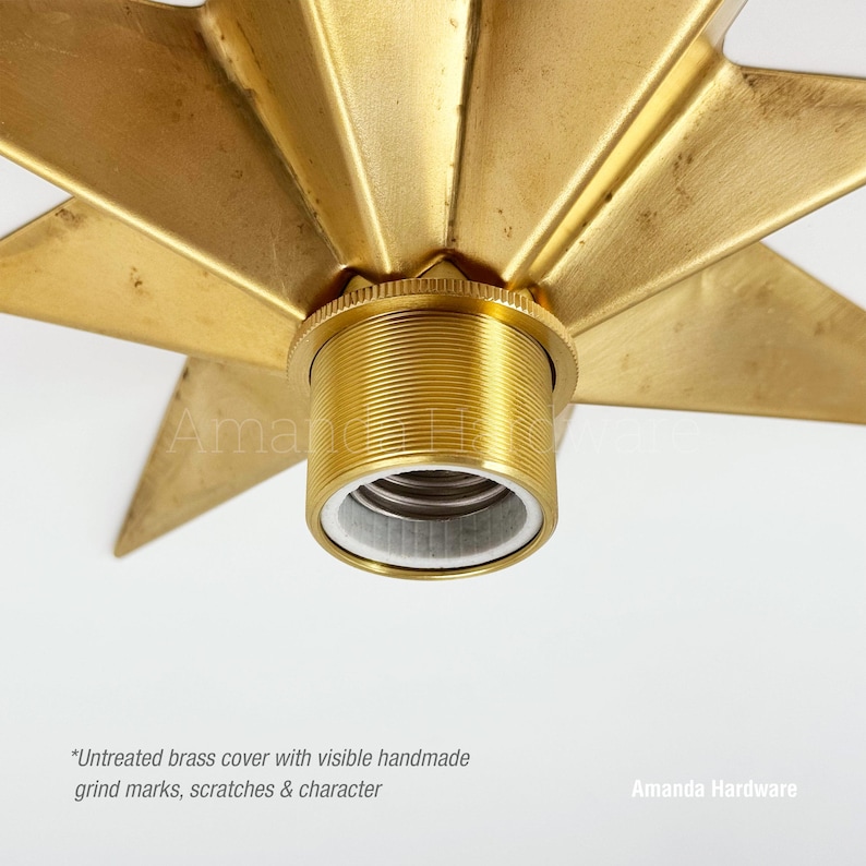 May include: A star-shaped brass light fixture cover featuring a central threaded socket. The metal surface displays a natural, untreated finish with visible handmade grind marks, small scratches, and textural character throughout the design.