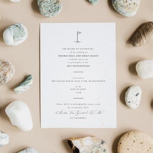 May include: A wedding invitation for Thomas Ball and Emily Mason. The invitation is printed on textured paper and features a golf club icon. The invitation states that the wedding will be held at The Manor House Golf Club, Blackthorne on June 20th at 11pm. The invitation also includes the RSVP information and the names of the co-chairmen, Amelia Var Gust and Lu Na.
