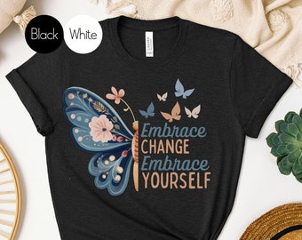 Könnte beinhalten: Schwarzes T-Shirt mit einem bunten Schmetterlingsmotiv und dem Text "Embrace Change Embrace Yourself".