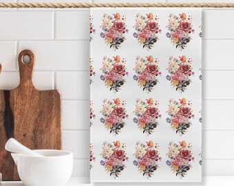 May include: A white kitchen towel with a repeating pattern of pink, red, and yellow floral bouquets.
