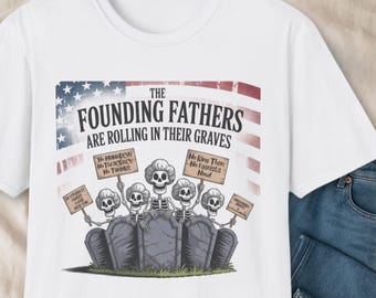 May include: White t-shirt featuring a graphic with the text "THE FOUNDING FATHERS ARE ROLLING IN THEIR GRAVES." The design includes skeletons rising from graves, holding signs with political statements. The top of the design has a flag-like pattern.