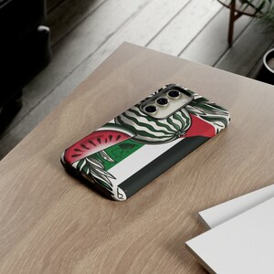 May include: A phone case with a watermelon and green and white striped design. The case has a black border and a camera cutout.