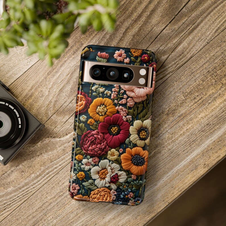 Puede incluir: Una funda para tel&eacute;fono con un dise&ntilde;o floral. La funda es negra con un borde dorado y presenta una variedad de flores coloridas, incluyendo rojas, rosas, amarillas y azules.
