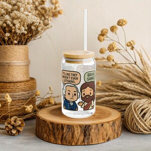 May include: A clear glass tumbler with a bamboo lid and a straw. The tumbler features cartoon illustrations of two figures with speech bubbles that read, "IT'S LIKE THEY WEREN'T EVEN LISTENING," and "BRUH SAME!"