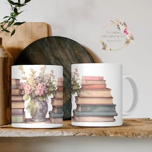 May include: Two white ceramic mugs with floral and book designs. One mug features a vase of pink and yellow flowers with a stack of books. The other mug has a stack of books. The mugs are on a wooden shelf.