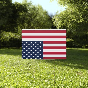 May include: A red, white, and blue American flag yard sign with the stars upside down. The sign is made of corrugated plastic and is designed to be displayed in a yard.