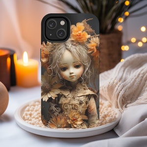 May include: A phone case with a design of a porcelain doll with flowers in her hair. The doll is wearing a white dress with lace details. The phone case is black and has a camera lens cutout.