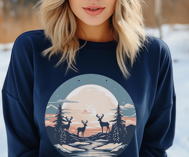 May include: A navy blue sweatshirt with a graphic print of a full moon, three deer, and a forest scene. The moon is a pale yellow color with a crescent moon shape in the center. The deer are silhouetted against the moon and forest.