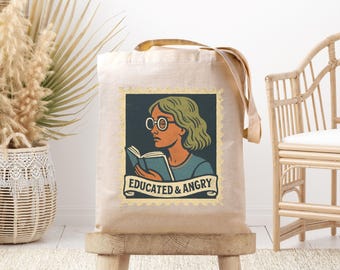 Könnte beinhalten: Beige Canvas-Tragetasche mit einer Illustration im Vintage-Stil einer Person mit Brille, die ein Buch liest. Die Illustration ist mit einem goldenen Rahmen versehen und enthält den Text "EDUCATED & ANGRY" auf einem Banner.
