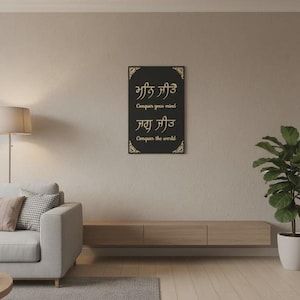 May include: A black rectangular wall art piece with gold text that reads "Conquer your mind" and "Conquer the world". The artwork is framed with gold decorative corners and is mounted on a beige wall.