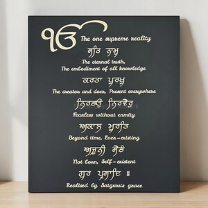 Könnte beinhalten: Schwarzes rechteckiges Wandbild mit weißem Text. Der Text enthält Sätze auf Englisch und einer anderen Sprache. Das Kunstwerk ist ein spirituelles oder religiöses Stück, mit den Worten "The one supreme reality" sichtbar.