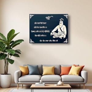 May include: A blue and white framed print with a white silhouette of a man sitting with a book in his lap. The print features text in the Gurmukhi script, which reads: "ਮੁਹਿ ਮੰਗਾਂ ਸੋਈ ਦੇਵਦਾ ਹਰਿ ਪਿਤਾ ਸੁਖਦਾਇਕ ॥ ਗਿਆਨੁ ਰਾਸਿ ਨਾਮੁ ਧਨੁ ਸਉਪਿਓਨੁ ਇਸੁ ਸਉਦੇ ਲਾਇਕ ॥ ਧੰਨ ਧੰਨ ਬਾਬਾ ਦੀਪ ਸਿੰਘ ਜੀ".