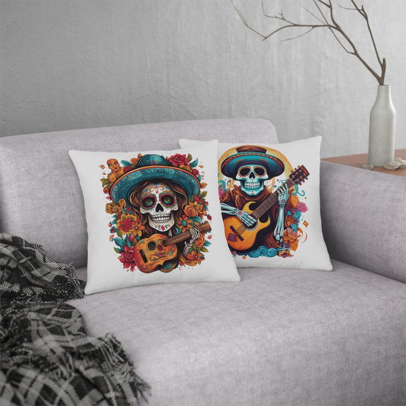 May include: Two white throw pillows with colorful Day of the Dead sugar skull designs. Each skull is wearing a sombrero and playing a guitar.