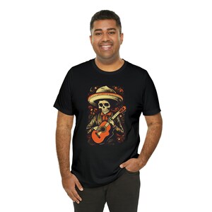 May include: Black t-shirt with a graphic of a skeleton wearing a sombrero and playing a guitar.