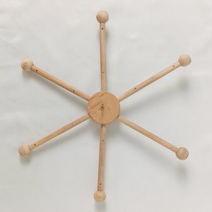 May include: A wooden mobile frame with six arms and six wooden balls at the ends of each arm. The frame is designed to hold a mobile.