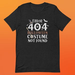 May include: Black t-shirt with a white graphic that says "ERROR 404 HALLOWEEN COSTUME NOT FOUND". The graphic also includes a witch's hat, a broom, and spiders.