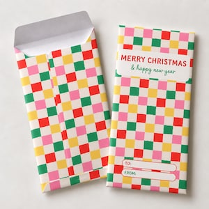 Puede incluir: Dos sobres rectangulares de papel con un colorido patrón de cuadros en rojo, verde, amarillo y rosa. Un sobre está abierto, mientras que el otro está cerrado y muestra el texto MERRY CHRISTMAS & happy new year, con campos para TO: y FROM:.