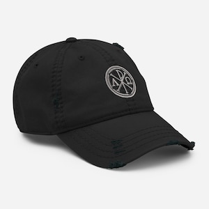 Puede incluir: Gorra de béisbol negra desgastada con un círculo bordado blanco que contiene las letras griegas Alfa y Omega, una cruz y la letra P.
