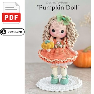 Peut inclure: Patron de jouet "Pumpkin Doll" au crochet. La poupée a des cheveux blonds bouclés, des joues roses et porte une robe orange avec un nœud vert. La poupée tient une petite citrouille et se tient sur un napperon blanc.