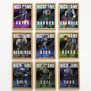 May include: Nine framed posters featuring characters from the video game Valorant. Each poster has a different character, including Astra, Harbor, Chamber, Deadlock, Neon, Gekko, Kay/O, Skye, and Yoru. The posters are all in a similar style, with a black background and white text.